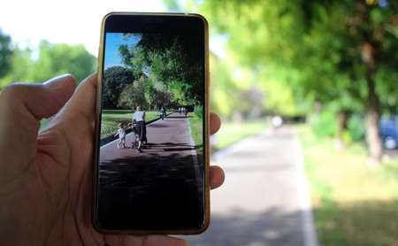 Smartphone photo of a mom with a stroller and her baby girl in the urban park in Summerの写真素材