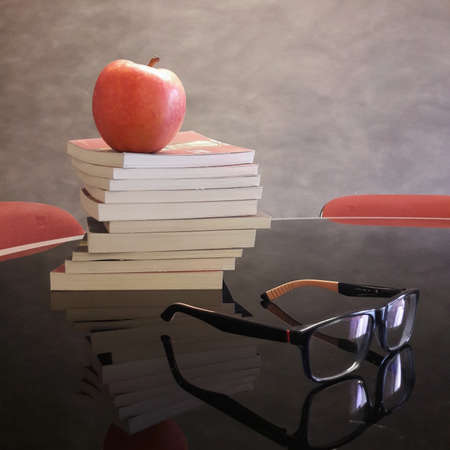 Books, eyeglasses and an apple on the deskの写真素材