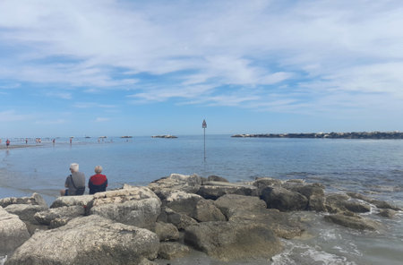 Elderly couple sitting on the rocks and looking at the seaの写真素材