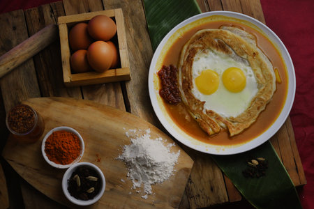 prata canai style style breakfast, fried egg with curry paste on wooden backgroundの写真素材