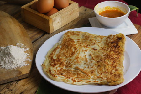 prata canai style pancake with curry and egg on wood background.Thai foodの写真素材