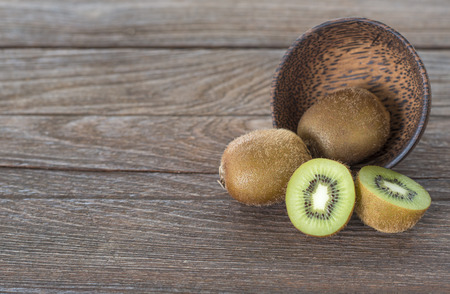 kiwi in wooden bowl on wooden backgroundの写真素材