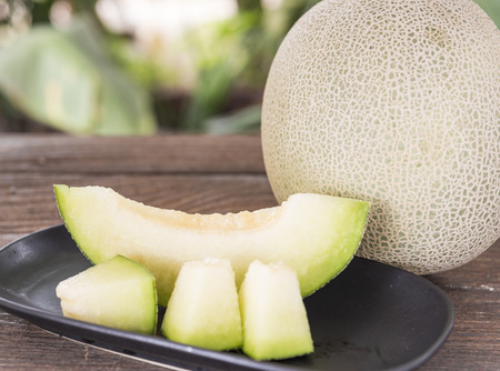 Full and sliced ââcantaloupe melon on wooden floor.の写真素材