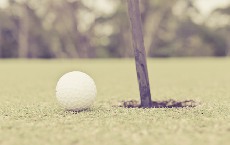 Golf ball on lip of cup of golf in a retro style.の写真素材