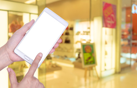 Human hand hold and touch screen smart phone, tablet,cellphone on blurred Shopping mall background.の写真素材