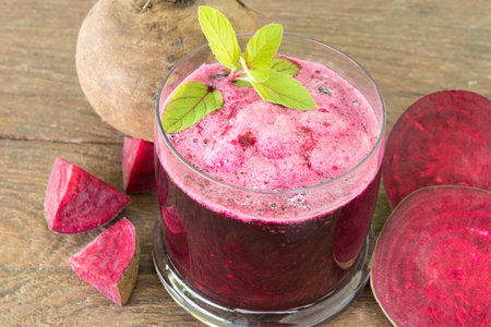 Beetroot juice in a glass on a wooden table with natural light.