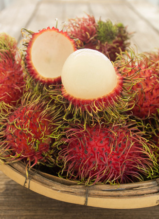 rambutan asian fruit in basket on wooden table.の写真素材