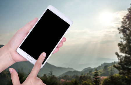 Human hand hold and touch screen smart phone, tablet,cellphone on blurred Park background.の写真素材