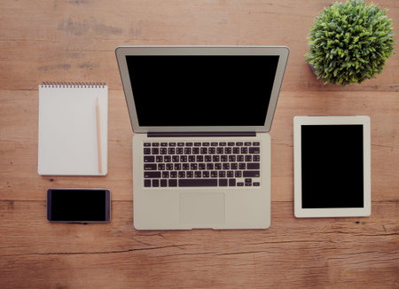 Open laptop computer with  tablet , smartphone , notebook on wooden desk. top view