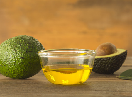 glass bowl of avocado essential oil with fresh avocado fruit closeupの写真素材