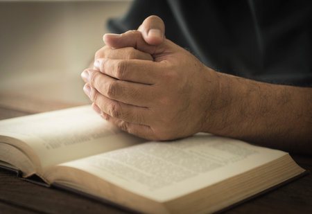 Hands of a man in prayer on a Holy Bible . religion concept