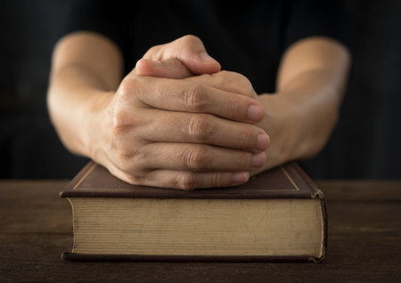 Hands of a human in prayer on a Holy Bible . religion concept.