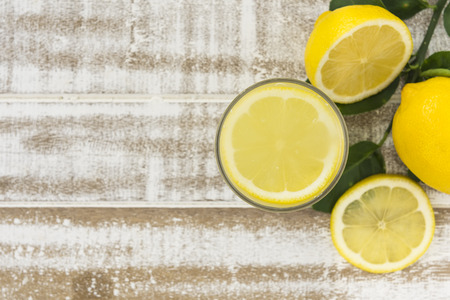 Fresh lemon juice in a glass placed on a wooden floor.の写真素材