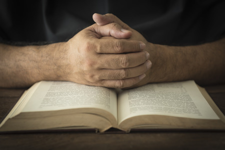 Hands of a man in prayer on a Holy Bible . religion conceptの写真素材
