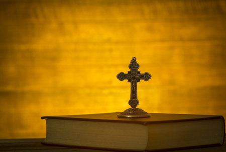 The cross is located on the Bible, against a backdrop of dark wood.の写真素材