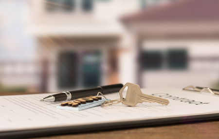 closeup house key on contract document with house key in house background.の写真素材