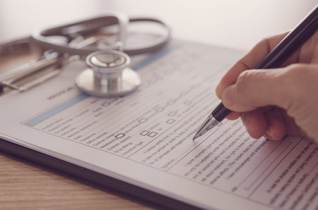 closeup pen in hand's doctor notes data on medical document.