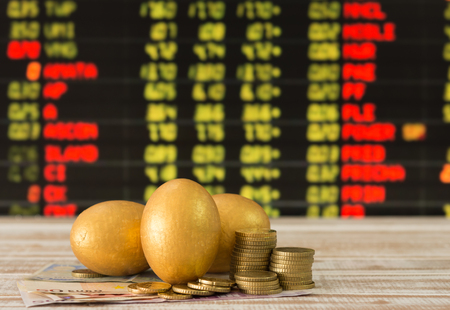 golden eggs,coins,banknote with the stock price board background. selective focusの写真素材