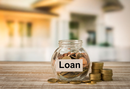 Golden coins in money jar with loan label. Concept of financial planning for housing, home savings, home loans.の写真素材