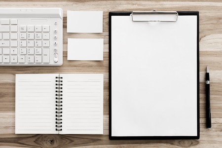 Mock up office desk table with keyboard, notebook, business card, clipboard, pen. Top view with copy space. vintage style.の写真素材