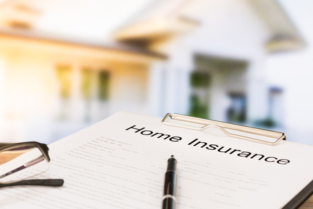 Insurance policy and a pen with home in background. Home insurance concepts.の写真素材