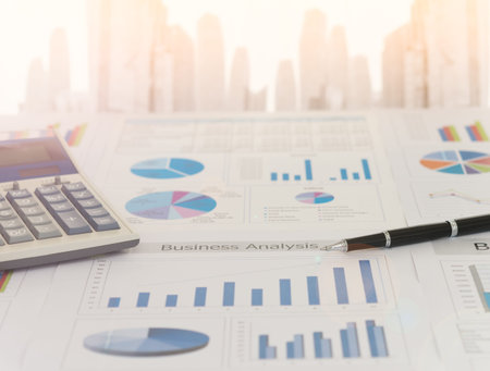 Pen on earnings report with calculator on desk of financial adviser. Concept of invest planning, analyze return on investment.の写真素材