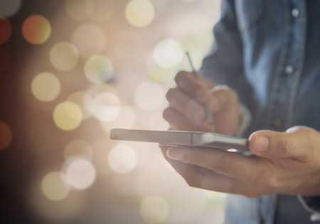 Human using mobile smartphone for business on the background bokeh.の写真素材