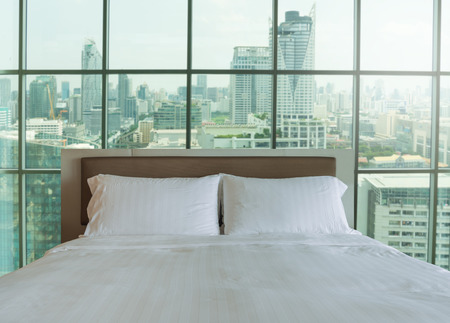 Bedroom in the morning light. Big comfortable double bed in luxury bedroom with city views.の写真素材