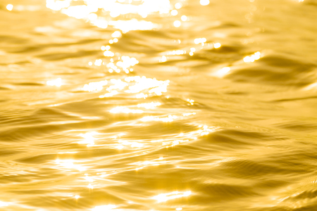 Abstract Solar reflective surface gold background. Bokeh effect. Smooth light gold waves lines and Lens Flares.の写真素材
