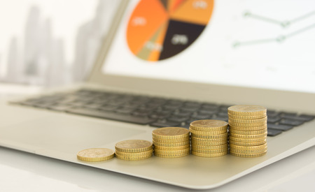 Coins stack on laptop computer in office. Concept of investment growth,investment plan, investment management, investment portfolioの写真素材