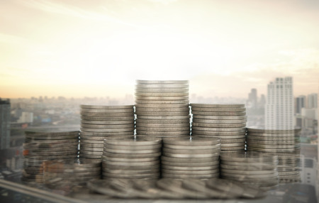 finance and value money growth concept. coins stack diagram with city business background.の写真素材