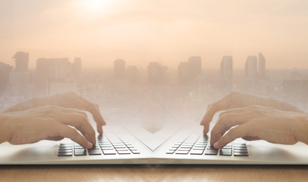 Internet online digital technology concept. Human using laptop computer and city background copy space.の写真素材