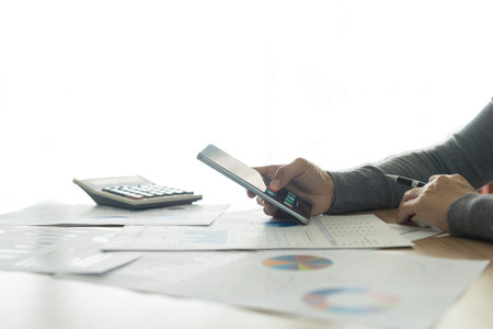 Accountants are using a smartphone to help analyze the data on the table.