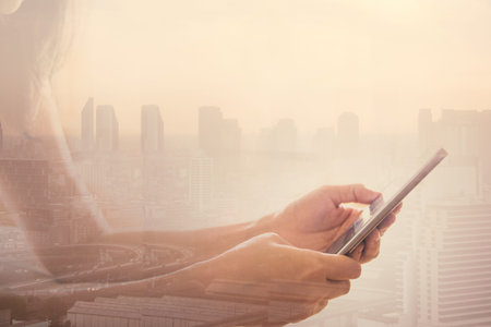 Double exposure Woman hand using smart phone against city background. The concept of network...