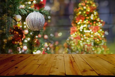 Christmas and New Year concept. Wooden table top with Christmas tree with decorations blurred from the celebration.の写真素材