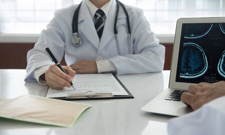 medical concept. doctor take notes on medical report with stethoscope on cardiogram chart on desk at doctor office.の写真素材