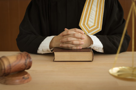 Attorney sitting in courtroom with law books, scales of justice and judge gavel on desk. law and...