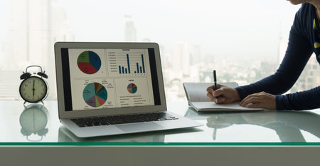 Business presentation report on computer screen on desk with women recording data on to schedule a...