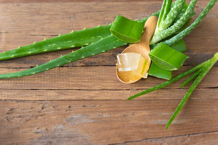 aloe vera gel on wooden spoon with aloe vera on wooden tableの写真素材