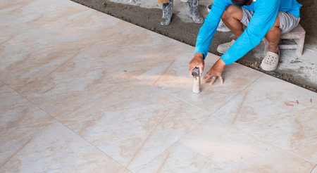 Close-up worker installing ceramic tiles floor in construction work.の写真素材