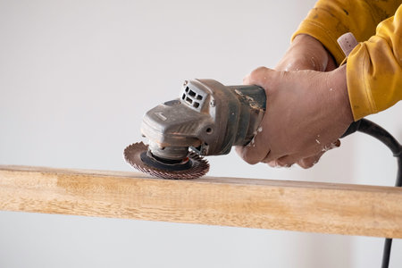 The carpenter is using a wood polishing machine to make the wood smooth.