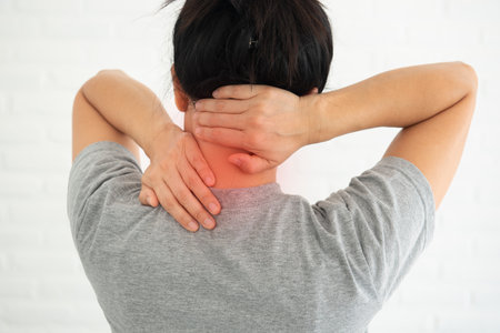 Rearview of a young women's shoulder pain, neck pain. Red around the pain area.の写真素材