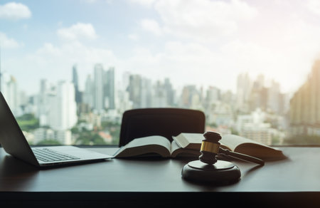 judges gavel, law books and computer on desk in lawyer office and city view. legislator and legal advice concept.の写真素材