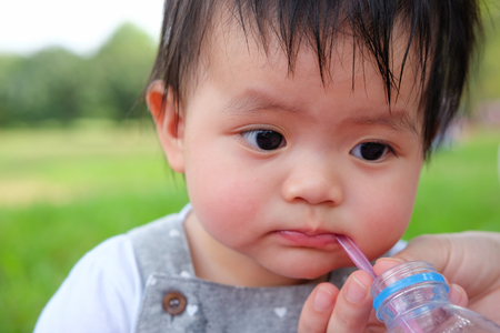 Cute Baby girl playing in the garden, close-up portrait, Portrait of a beautiful baby girl, baby drinking waterの写真素材