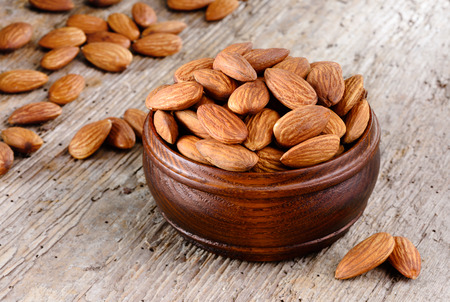 Shelled almonds in a bowl on wooden background. Organic food.の写真素材