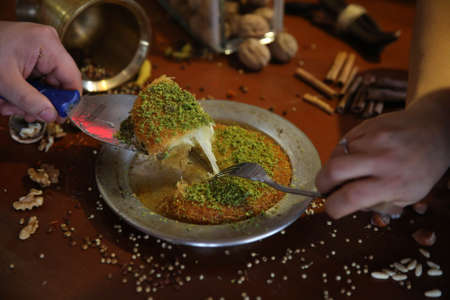 Turkish dessert kunefe, kunafa, kadayif with pistachio powder and cheese hot eaten a sweetの写真素材