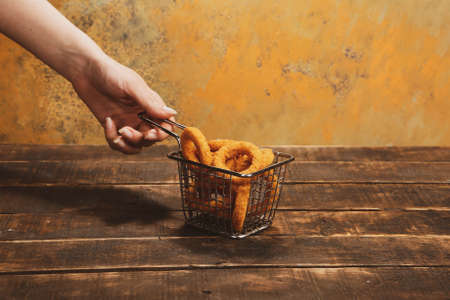Delicious snack plate, french fries, onion rings, spring rolls or sausages on the tableの写真素材