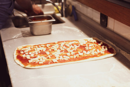 Pizza chef put sauce on base in a commercial kitchen