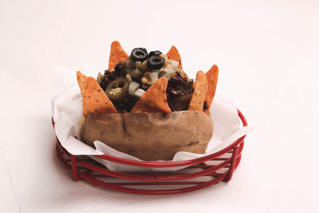 Baked kumpir potato stuffed with the cheese, sausage, olives, peppers and corn