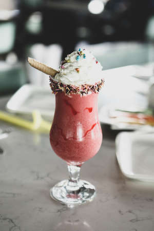 Glass of raspberry milkshake with whipped cream and fresh raspberriesの写真素材